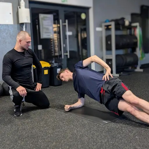 Marcel Gielezy podczas treningu personalnego instruuje klienta, jak prawidłowo wykonać ćwiczenie side plank