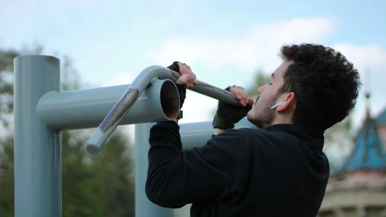 Mężczyzna podciąga się podchwytem w parku na drążku